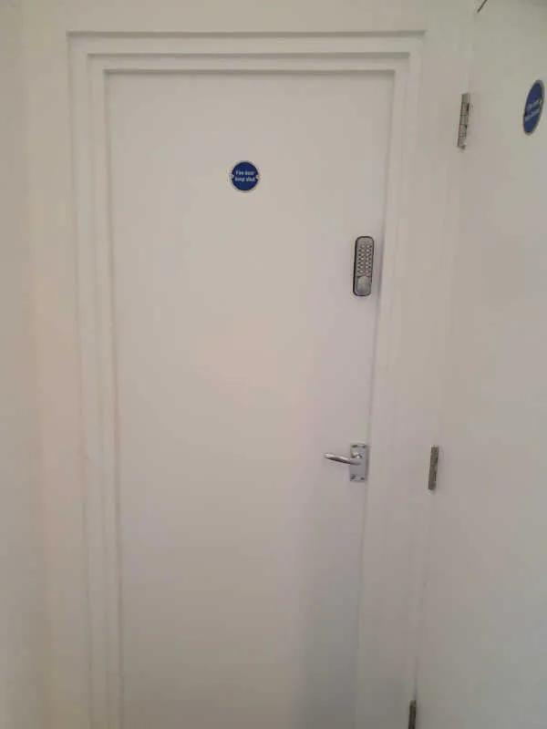 Completed white fire door with closer and safety signage