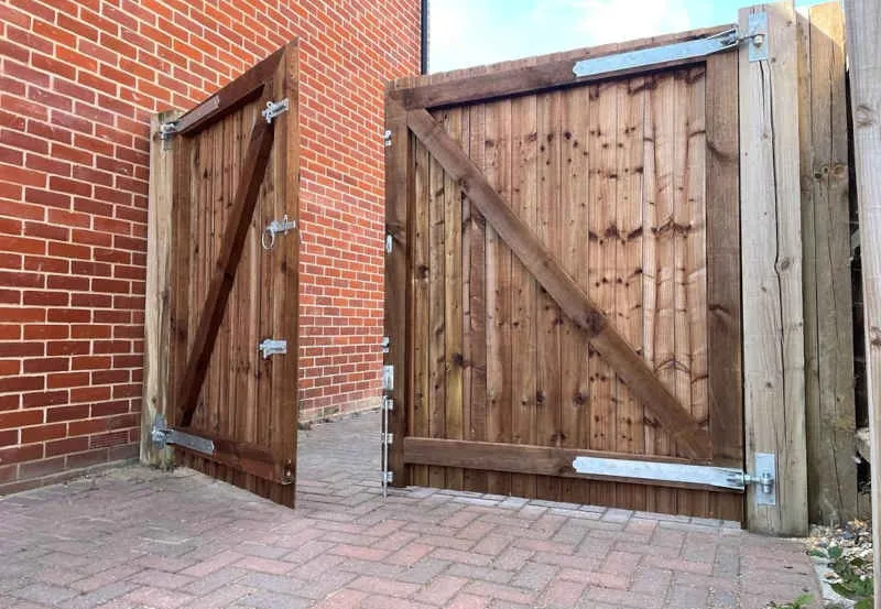 Completed timber garden gate and fencing beside a brick residential property